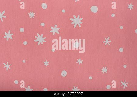 Papier rose doux avec motif de flocon de neige blanc, idéal comme fond de fête ou papier d'emballage pour les vacances d'hiver. Photo Banque D'Images