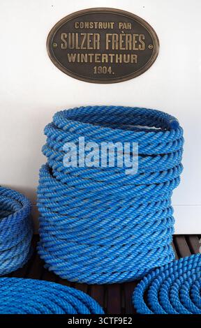 Vevey, Suisse - 24 septembre 2025 : corde bleue enroulée avec une plaque vintage sur un mur blanc. Banque D'Images