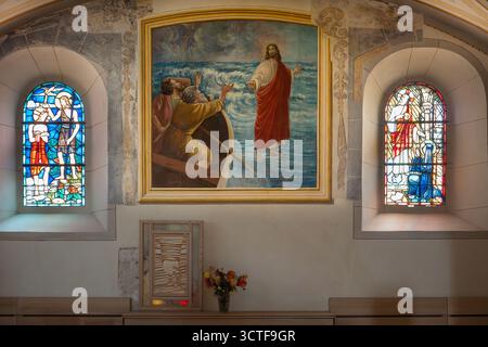Yvoire, France - 25 septembre 2025 : intérieur de l'église avec vitraux et peinture de Jésus marchant sur l'eau. Banque D'Images
