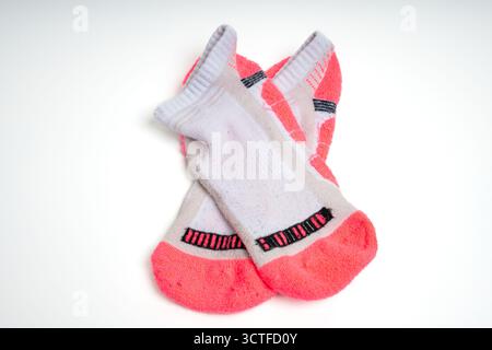 Paire de chaussettes de sport roses et blanches utilisées sur fond blanc isolé. Concept de fitness, athlétique et de performance Banque D'Images