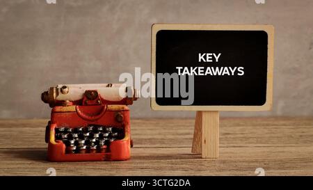 Key Takeaways écrit sur un mini tableau noir à côté d'une machine à écrire rouge vintage Banque D'Images