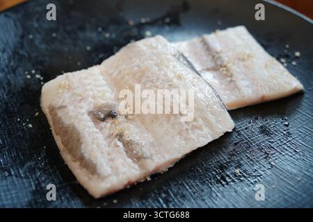 Filets d'anguille crue fraîche sur une assiette noire, prêts pour la cuisson Banque D'Images