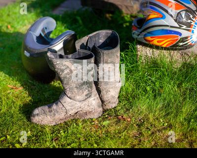 une paire de bottes de motocross sales et de casques est tombée sur le sol et doit être nettoyée Banque D'Images