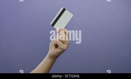 Homme tenant une carte de crédit avec fond violet présentant le concept financier dans un cadre isolé mettant en évidence l'identité et les thèmes de paiement. Banque D'Images