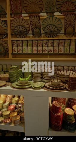 Des céramiques colorées exposées dans un magasin de poterie mettant en valeur des bols, des assiettes et des tasses vibrants disposés soigneusement sur les étagères, mettant en valeur l'artisanat artisanal Banque D'Images
