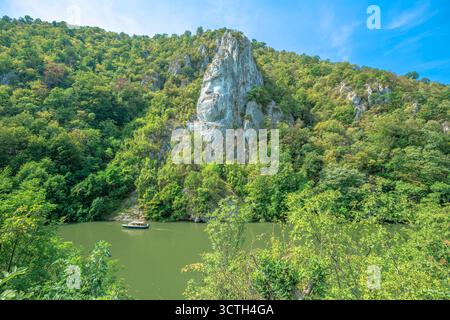 Roumanie - 1er septembre 2025 : le Danube coule à travers la gorge Iron Gates en Roumanie, avec l'ancienne sculpture du roi Dace Decebalus sculptée dans Banque D'Images
