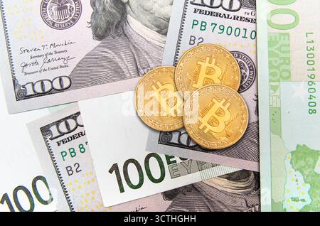 Les pièces bitcoin dorées sont disposées sur les billets de banque en dollars américains, soulignant le contraste entre la monnaie numérique et la monnaie fiduciaire. Banque D'Images