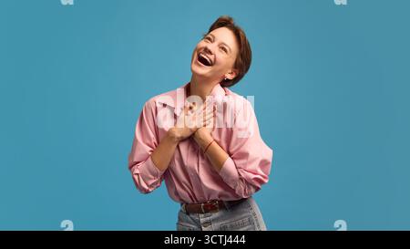 Heureuse jeune femme avec les mains sur la poitrine exprimant gratitude et joie Banque D'Images