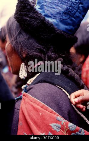 Femme et enfant, Ladakh, Inde, 1988. Femme Ladakhi à un festival religieux bouddhiste. Elle porte un chapeau en soie doublé de fourrure et des boucles d'oreilles en perles. Banque D'Images