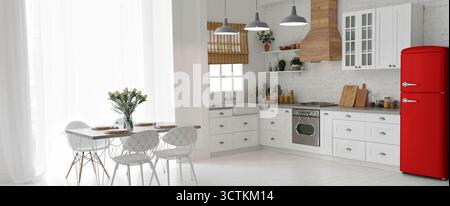 Réfrigérateur rouge et table à manger avec chaises dans la cuisine spacieuse. Design intérieur élégant Banque D'Images