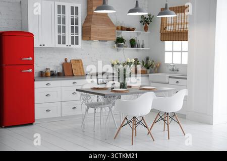 Réfrigérateur rouge et table à manger avec chaises dans la cuisine. Design intérieur élégant Banque D'Images