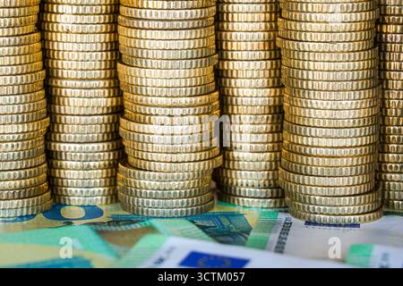 Gros plan de pièces en euros empilées avec des billets en euros en dessous, symbolisant l'épargne, la richesse, les opérations bancaires, les investissements, et l'économie européenne Banque D'Images