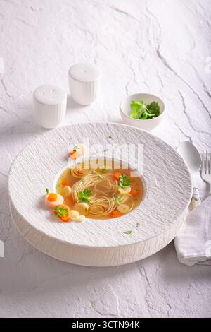 Soupe de bouillon exclusive comme art culinaire sur l'assiette. Soupe de bouillon avec une décoration exquise. Banque D'Images