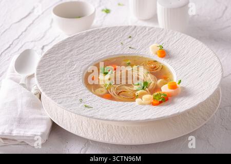 Soupe de bouillon exquise comme art culinaire sur l'assiette. Soupe au bouillon comme plat de placage exclusif. Banque D'Images
