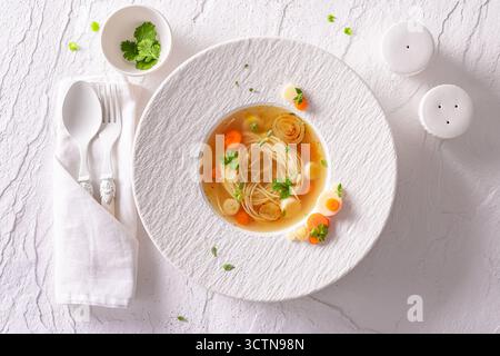 Soupe de bouillon exclusive avec présentation haut de gamme sur assiette. Soupe au bouillon comme plat de placage exclusif. Banque D'Images