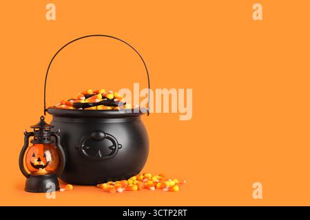 Chaudrons de savoureux cors de bonbons d'Halloween et lanterne sur fond orange Banque D'Images