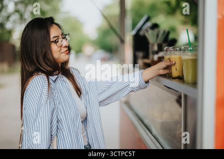 Femme profitant d'une boisson rafraîchissante à un stand de nourriture en plein air Banque D'Images