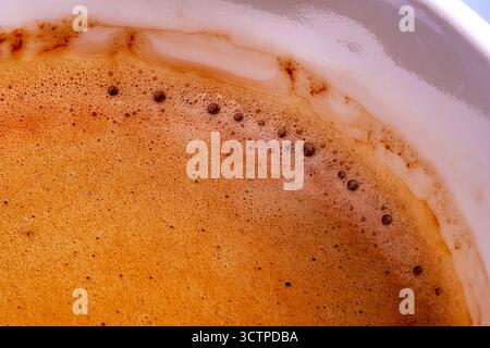 Macro gros plan de la surface de la crème espresso Macro dose de crème espresso riche dans une tasse blanche présentant de fines bulles. Texture crémeuse et tons bruns chauds. Banque D'Images