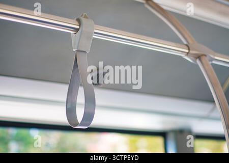 Gros plan d'une dragonne dans les transports en commun, attachée à une barre métallique suspendue. La poignée assure la stabilité pour les passagers debout. Banque D'Images