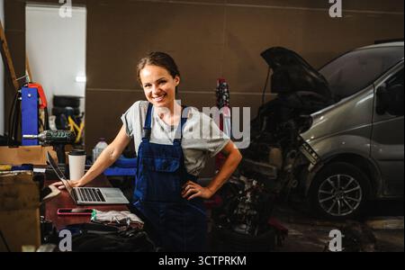 Portrait de mécanicien automobile féminin dans le garage de réparation automobile local. Banque D'Images