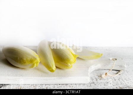 Endives belges crues fraîches (chicorée) isolées sur fond de bois. Nourriture saine et végétarienne. Directement au-dessus. Banque D'Images