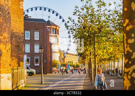 Vue sur le coucher du soleil de la vieille ville de Dusseldorf avec grande roue. Touristes appréciant la lumière chaude du soleil marchant sur le talus Banque D'Images
