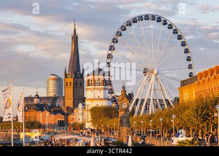 Vue panoramique en soirée sur le remblai du Rhin dans la vieille ville de Dusseldorf avec grande roue et église Saint-Lambert Banque D'Images