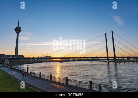 Vue colorée sur le coucher du soleil du paysage urbain de Dusseldorf avec la célèbre tour du Rhin, la zone Medienhafen et le pont Rheinkniebrücke les uns à côté des autres Banque D'Images