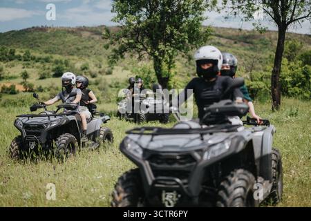 Groupe profitant de l'aventure en quad à travers un terrain extérieur luxuriant par une journée ensoleillée Banque D'Images