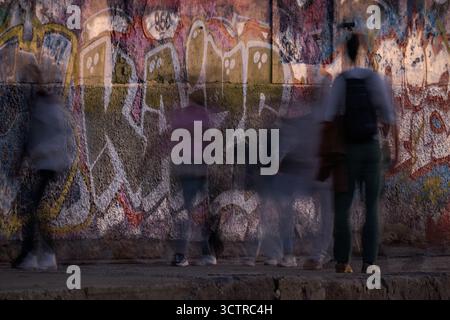 Scène de rue urbaine avec flou de mouvement de personnes marchant devant le mur de Graffiti – Art urbain abstrait et photographie de nuit Banque D'Images