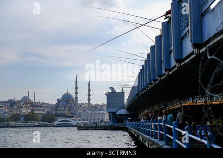 02 OCT 2025 - Istanbul, Turquie - hommes locaux pêchant avec des cannes du pont de Galata montrant la vieille ville et les mosquées en arrière-plan Banque D'Images