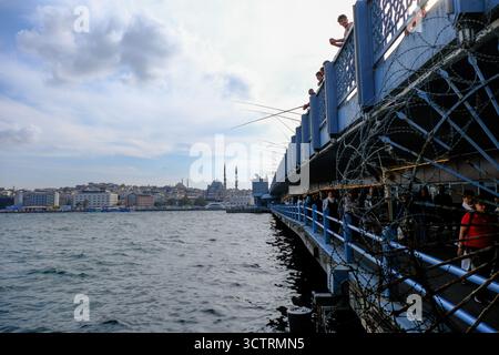 02 OCT 2025 - Istanbul, Turquie - hommes locaux pêchant avec des cannes du pont de Galata montrant la vieille ville et les mosquées en arrière-plan Banque D'Images