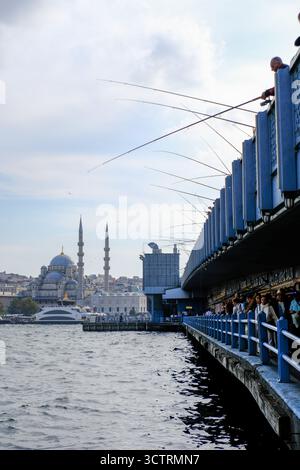 02 OCT 2025 - Istanbul, Turquie - hommes locaux pêchant avec des cannes du pont de Galata montrant la vieille ville et les mosquées en arrière-plan Banque D'Images