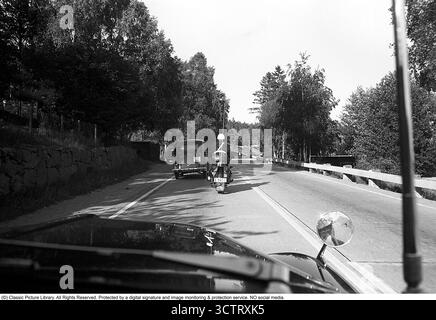 Surveillance de la circulation policière sur Riksetan, 1958. Entre 1945 et 1962, la Riksväg 1 a servi de route principale reliant Helsingborg à Stockholm. Aujourd'hui, cette route fait partie de la route européenne E4. Une vue depuis un véhicule de police surveillant la circulation sur la route achalandée. Un policier moto sur une moto BMW est à l'avant. Suède, 1958. Dans les années 1950, alors que le trafic automobile augmentait sur le réseau routier suédois en pleine expansion, les patrouilles de police jouaient un rôle crucial pour assurer la sécurité routière et l’application de la loi. Roland Palm réf. 3/533. Banque D'Images