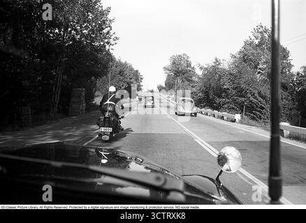Surveillance de la circulation policière sur Riksetan, 1958. Entre 1945 et 1962, la Riksväg 1 a servi de route principale reliant Helsingborg à Stockholm. Aujourd'hui, cette route fait partie de la route européenne E4. Une vue depuis un véhicule de police surveillant la circulation sur la route achalandée. Un policier moto sur une moto BMW est à l'avant. Suède, 1958. Dans les années 1950, alors que le trafic automobile augmentait sur le réseau routier suédois en pleine expansion, les patrouilles de police jouaient un rôle crucial pour assurer la sécurité routière et l’application de la loi. Roland Palm réf. 3/533. Banque D'Images