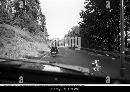 Surveillance de la circulation policière sur Riksetan, 1958. Entre 1945 et 1962, la Riksväg 1 a servi de route principale reliant Helsingborg à Stockholm. Aujourd'hui, cette route fait partie de la route européenne E4. Une vue depuis un véhicule de police surveillant la circulation sur la route achalandée. Un policier moto sur une moto BMW est à l'avant. Suède, 1958. Dans les années 1950, alors que le trafic automobile augmentait sur le réseau routier suédois en pleine expansion, les patrouilles de police jouaient un rôle crucial pour assurer la sécurité routière et l’application de la loi. Roland Palm réf. 3/533. Banque D'Images