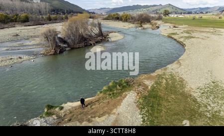 Vue aérienne de la rivière Motueka récemment inondée coupant dans des terres agricoles, et un agriculteur debout sur les rives, Kohatu, Tasman, Nouvelle-Zélande. Banque D'Images
