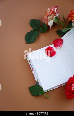 Matinée romantique avec des roses, un cahier et une tasse de cappuccino. Banque D'Images
