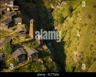 Vue aérienne des anciennes structures en pierre et des tours de guet accrochés aux falaises accidentées et ensoleillées de Dartlo, un village forteresse intemporel, Dartlo, Kakheti, Géorgie. Banque D'Images