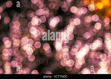 Bokeh rose flou — champ dense de petits orbes lumineux chauds sur fond sombre/noir. Un fond flou riche et abstrait parfait pour les papiers peints Banque D'Images