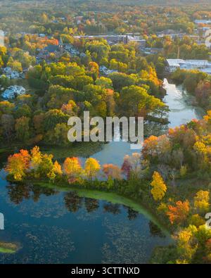 Vue aérienne du feuillage vibrant reflétant dans les eaux calmes de l'étang, entouré par les bâtiments de la ville, Easthampton, Massachusetts, États-Unis. Banque D'Images