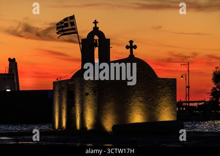 chapelle de panagia myrtodisia partiellement illuminée au coucher du soleil les deux croix sur le toit et le clocher se silhouettent sur le ciel rouge orangé vif Banque D'Images