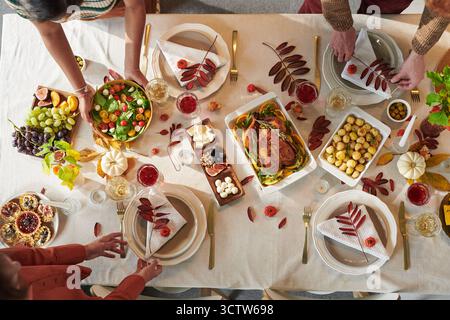 Adultes multiethniques partageant un repas de Thanksgiving autour de la table pendant la réunion de vacances Banque D'Images