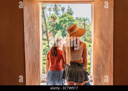 Mère et fille marchant par une porte à l'étage dans le Real Alcazar de Sevilla ou l'Alcazar Royal de Séville en Espagne, Europe. Banque D'Images