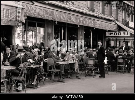 PARIS années 1930 les gens apprécient un café au Café le Dome à Paris France : scène de rue typiquement française traditionnelle parisienne. Les gens se détendent au Café le Dome, plein air animé, café en plein air à Montparnasse B&W photo 1930s. Banque D'Images