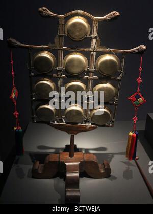 Une photographie de l'ulla ( ? ?), un instrument à percussion traditionnel coréen comprenant un ensemble de dix petits gongs accordés dans un cadre en bois orné. Chacun des gongs est de la même taille, mais ils produisent des sons différents en raison de leur épaisseur différente. Il est aussi appelé guunra ( ? ? ?) Et est attesté pendant la période Joseon (1392-1897), une dynastie qui a grandement influencé la culture coréenne et sa musique de cour élaborée. Les gongs sont frappés avec un maillet, dont une partie est visible à droite. c. 1850. Banque D'Images