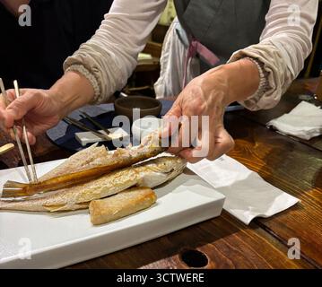 Photographie de mains préparant et servant une cuisine coréenne traditionnelle, en particulier du poisson grillé, à Gyeongju, en Corée du Sud. Cuisine coréenne, ou ? ? (Hansik), est réputé pour son utilisation d'ingrédients fermentés et de produits frais. 2025. Banque D'Images