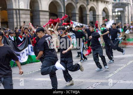 Un jeune manifestant souriant avec le drapeau palestinien peint sur son visage agite un tissu blanc lors d'une manifestation à Puebla. Banque D'Images
