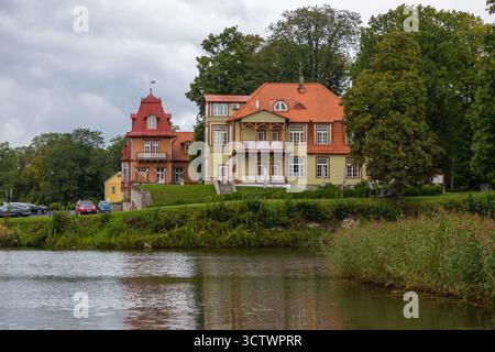 Kuressaare, Saaremaa, Estonie – 25 août 2021 : Villas restaurées en bois aux toits rouges situées près des douves près du château de Kuressaare entourées de verdure Banque D'Images