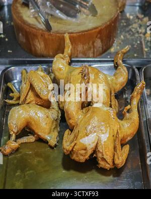 Poulet braisé entier dans une sauce de poisson sur un plateau. Plat principal traditionnel et savoureux de cuisine de rue thaïlandaise, prêt pour le portionnement et la nourriture. Banque D'Images